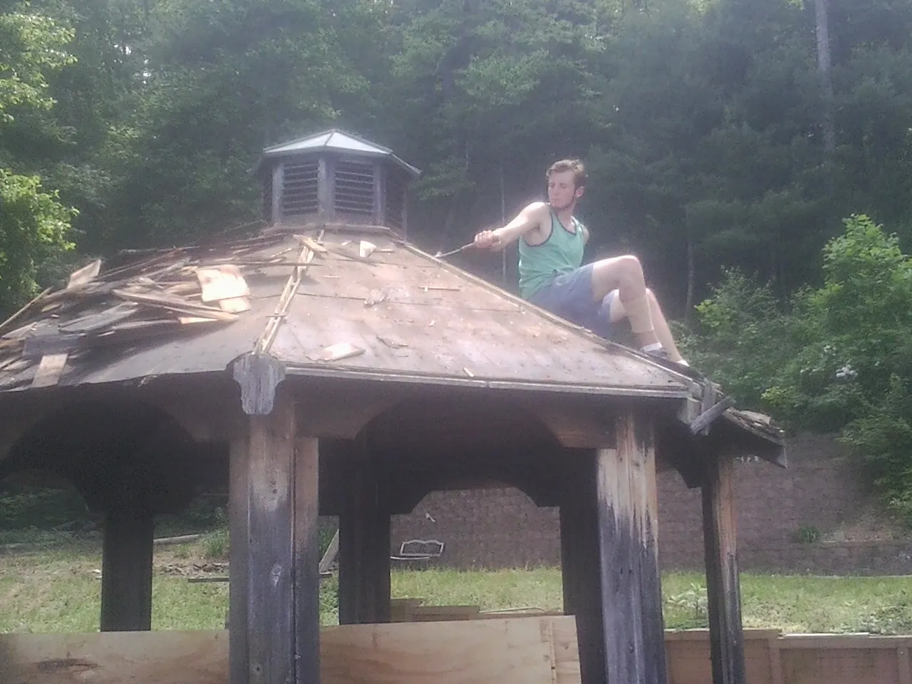 Tearing the old roof off a wooden gazebo before new shakes in Paramus