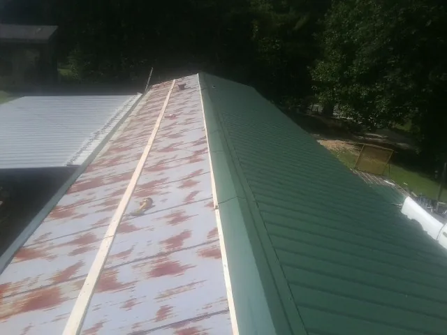 Old rusted panels beside newly installed green metal roofing — Wind Damage Roof Repair by Roofing Brothers in Paramus