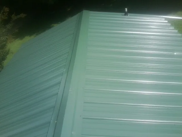 New green metal panels meeting at the ridge of a roof — Flat Roof Repair work by our crew in Paramus
