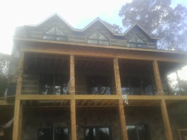Dormers and porch framing on a large log home under construction — Roof Coating work by our crew in Paramus