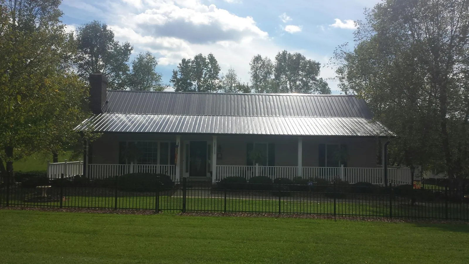 Gray metal roof on a brick ranch with a full width front porch — Gutter Guard Installation work by our crew in Paramus