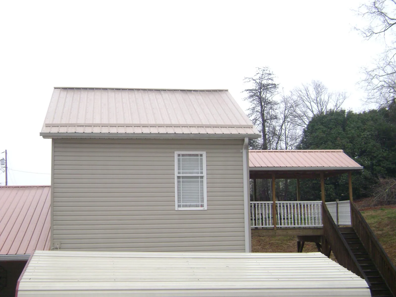 Tan metal roofs on a two story addition and attached porch, from a Roof Replacement job in Paramus
